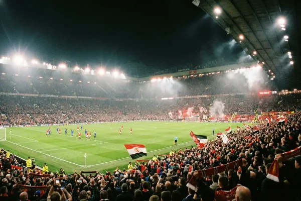 Estádio de futebol iluminado durante jogo noturno para apostas ao vivo