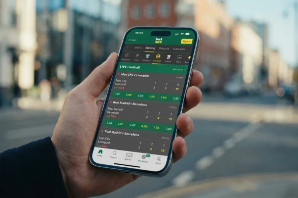 Mão a segurar telemóvel com aplicação de apostas desportivas aberta